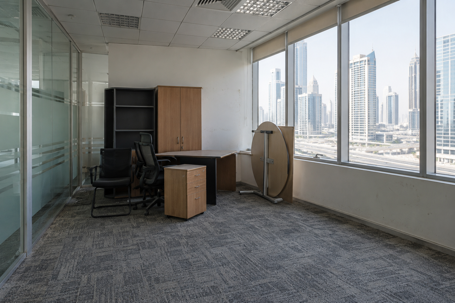 Used but serviceable office corner with existing furniture, carpet tiles and a glazed partition
